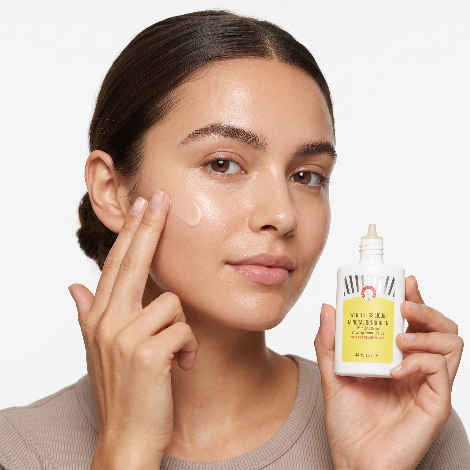 Who should try First Aid Beauty Weightless Liquid Mineral Sunscreen SPF 30 — model applying sheer sunscreen