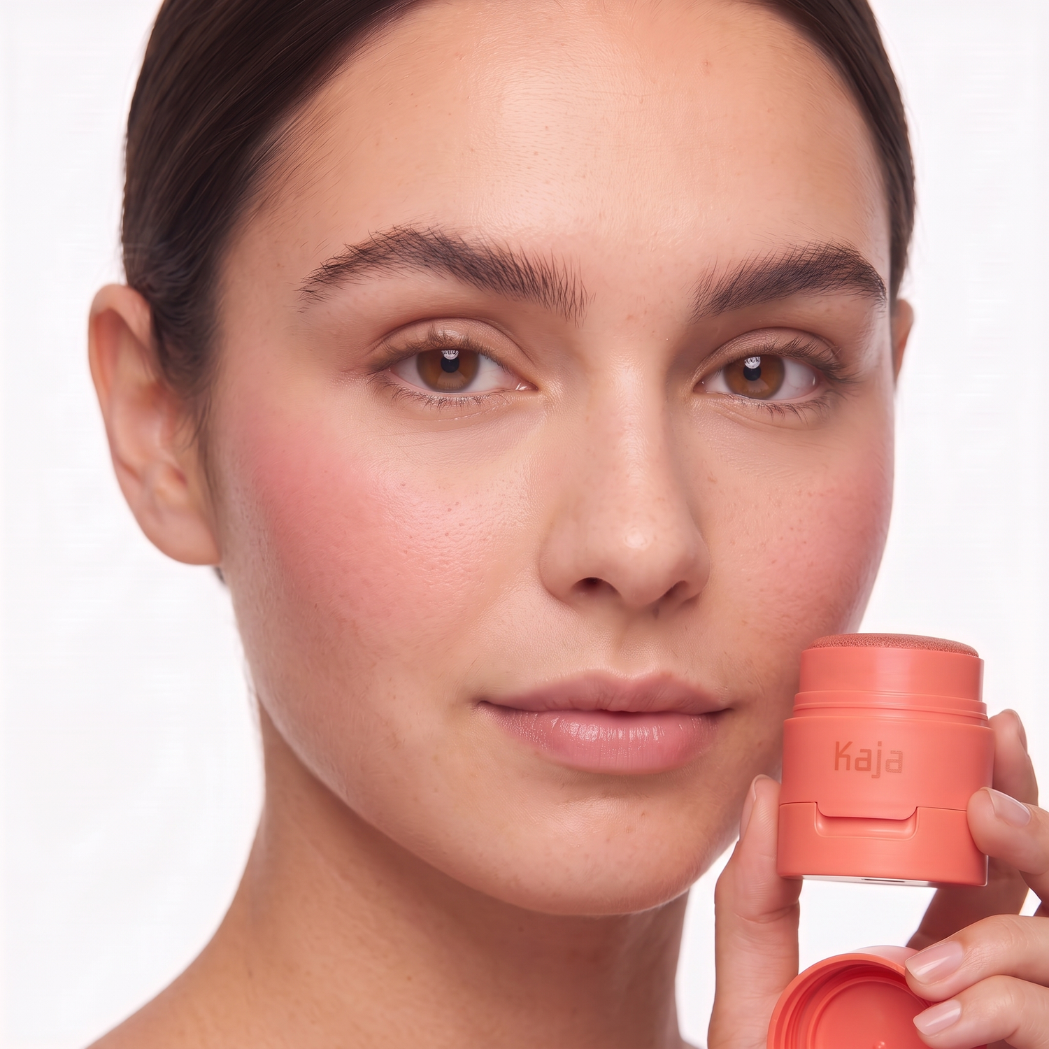 Who should try Kaja Cheeky Stamp blush — model with a soft blended flush holding the coral compact